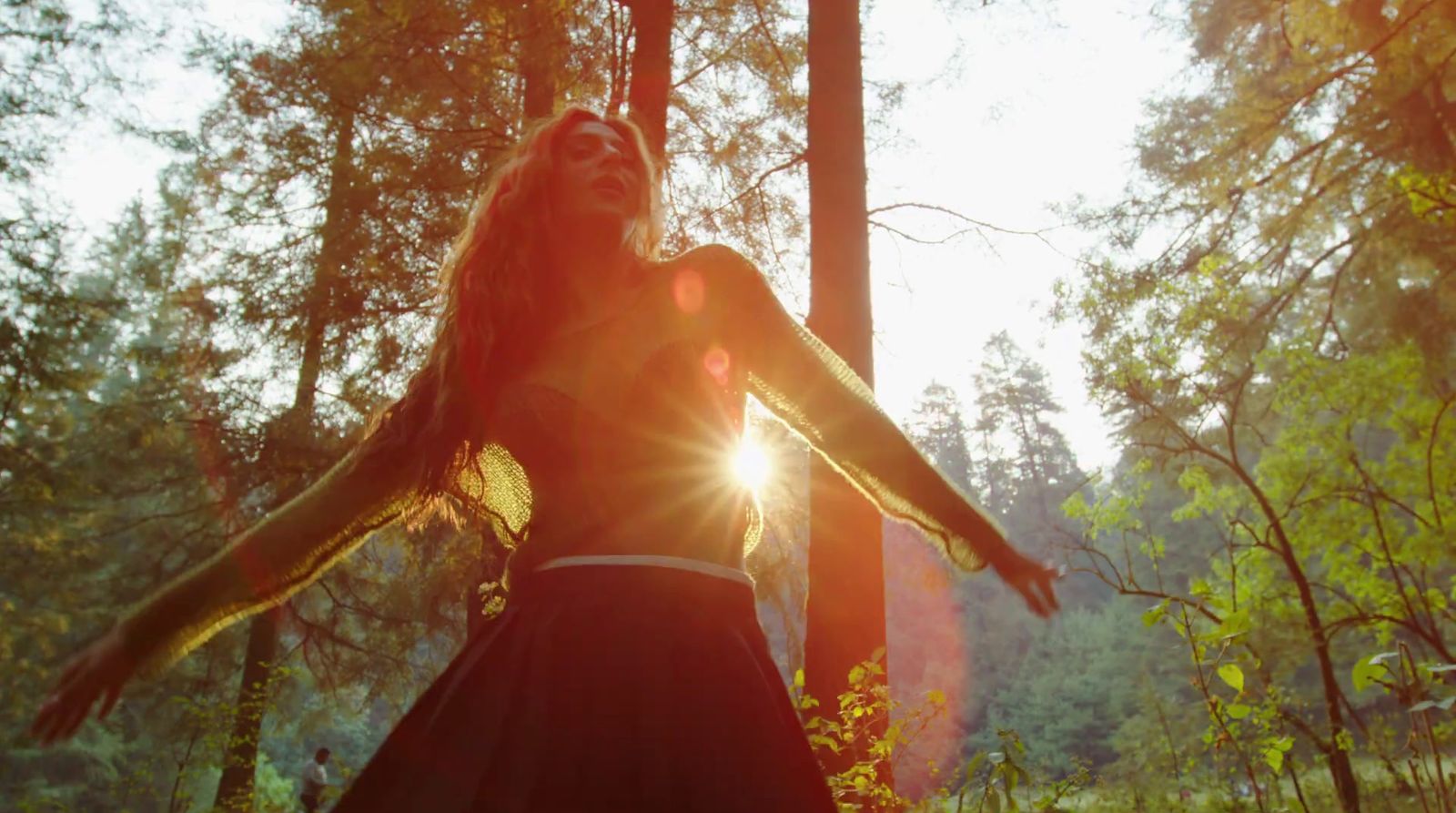 a woman standing in the middle of a forest