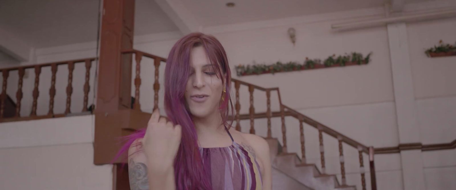 a woman with purple hair standing in front of a staircase