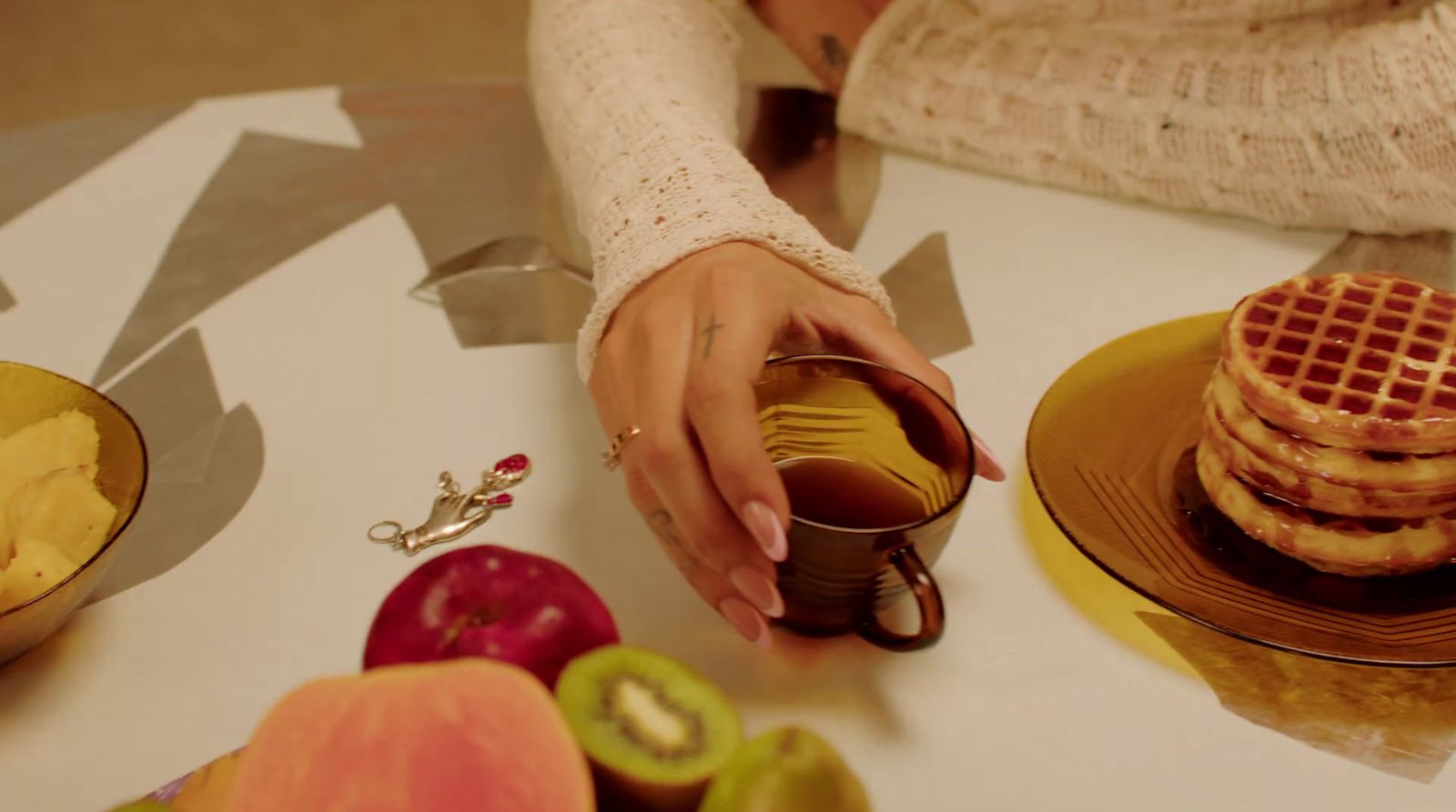 a woman is holding a cup of coffee and a stack of waffles