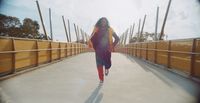 a woman is running across a bridge on a sunny day