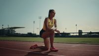 a woman sitting on a track holding a white frisbee