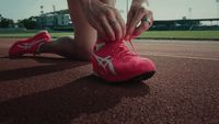 a person tying their shoe laces on a tennis court