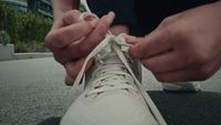 a person tying a pair of white sneakers