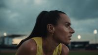 a woman in a yellow shirt is on a baseball field