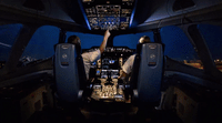 a man sitting in the cockpit of an airplane at night