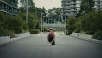 a woman kneeling down on the ground in a parking lot