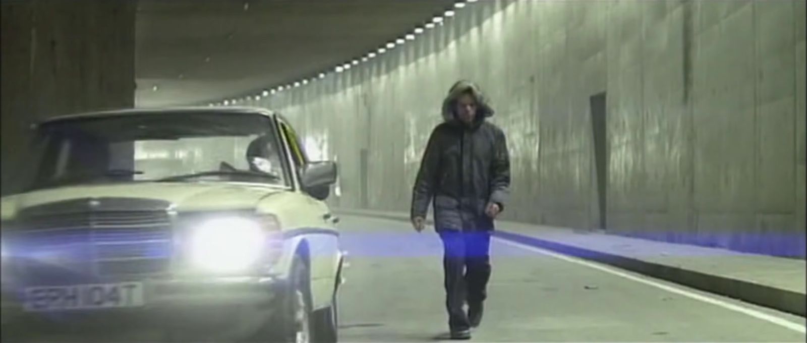 a man walking down a street next to a car