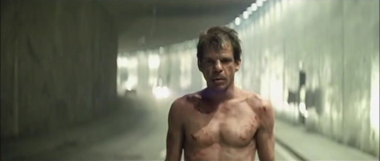 a man without a shirt standing in a tunnel