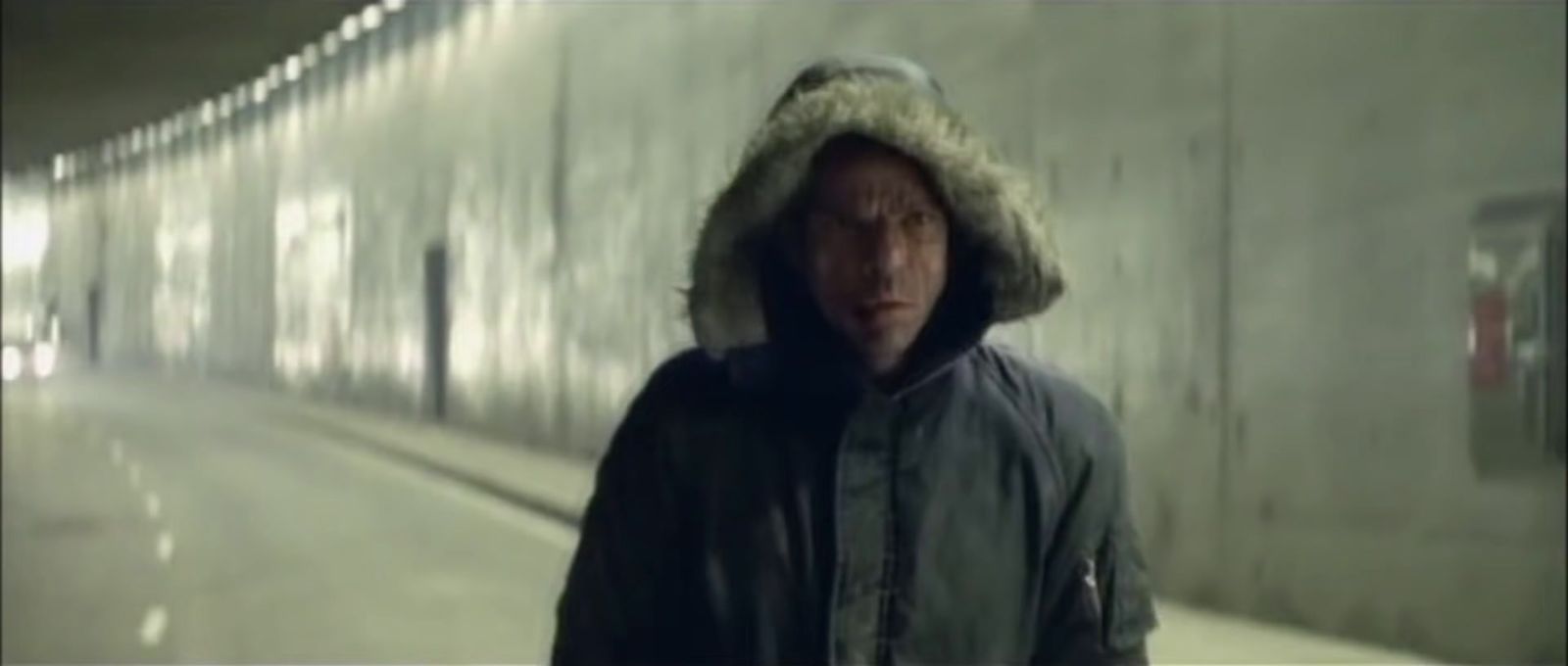 a man in a hooded jacket walking down a hallway