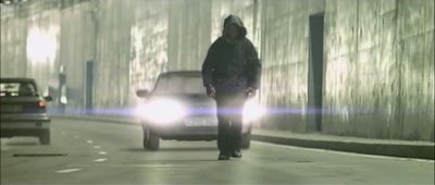 a man walking down a street next to a car