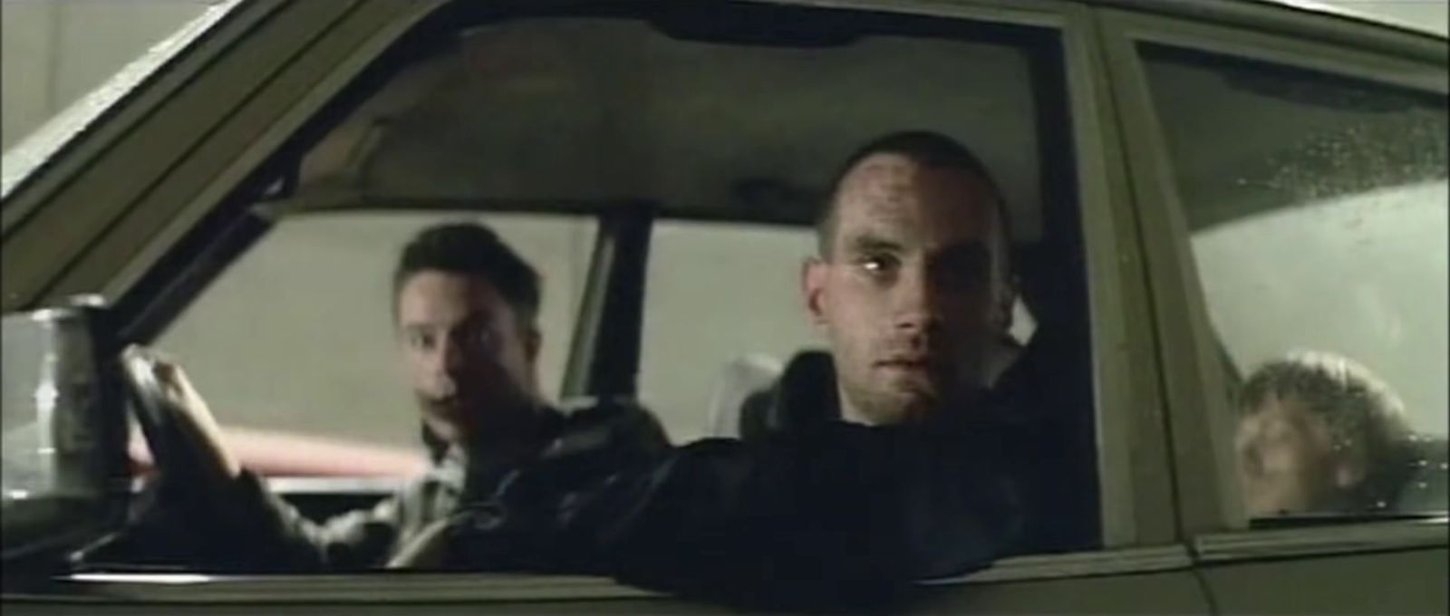 two men sitting in a car looking out the window