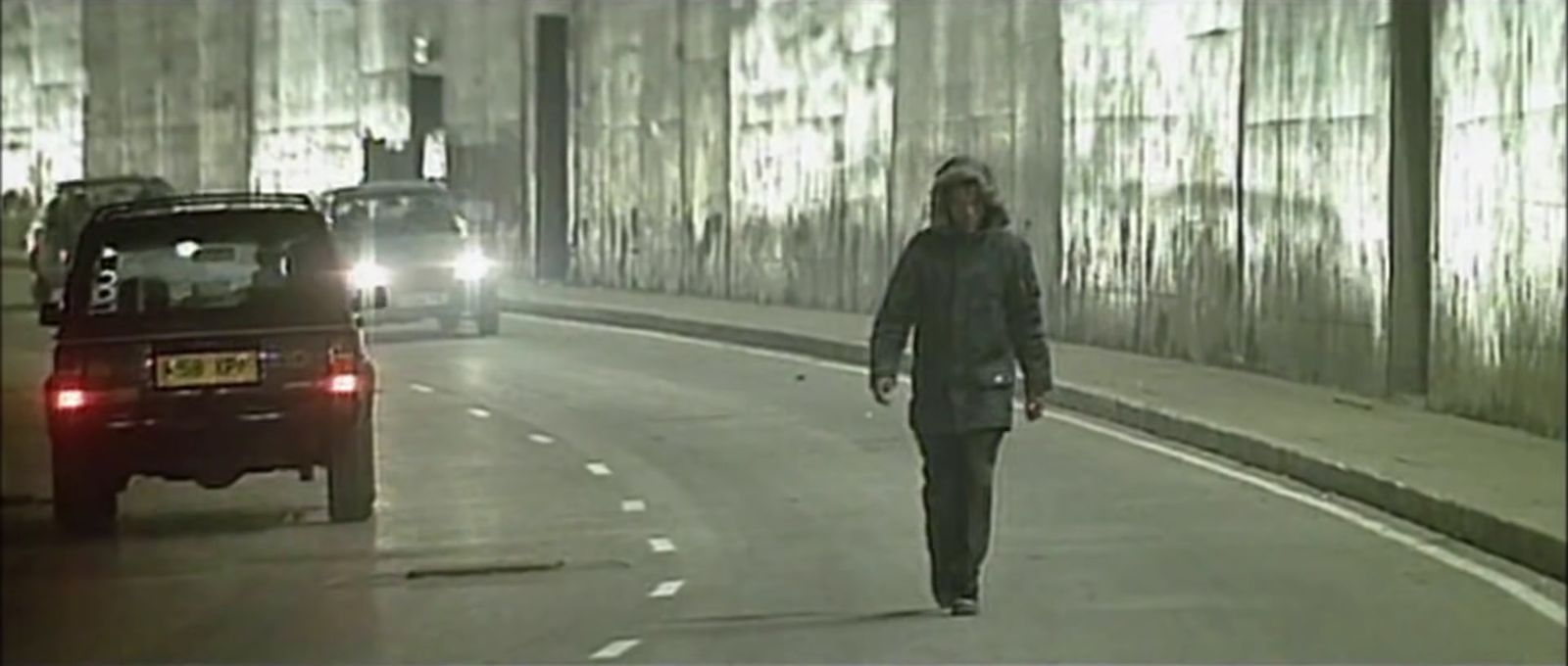 a man walking down a street next to a car