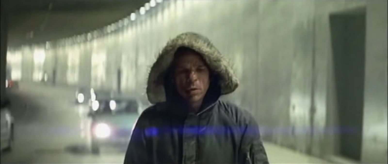 a man in a hooded jacket walking down a hallway