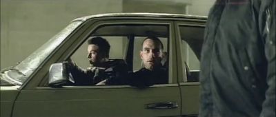 two men sitting in a car looking out the window