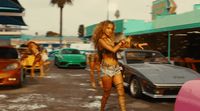 a woman walking down a street next to parked cars