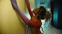 a woman in a red dress leaning against a wall