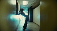 a woman standing in a hallway with a cell phone to her ear