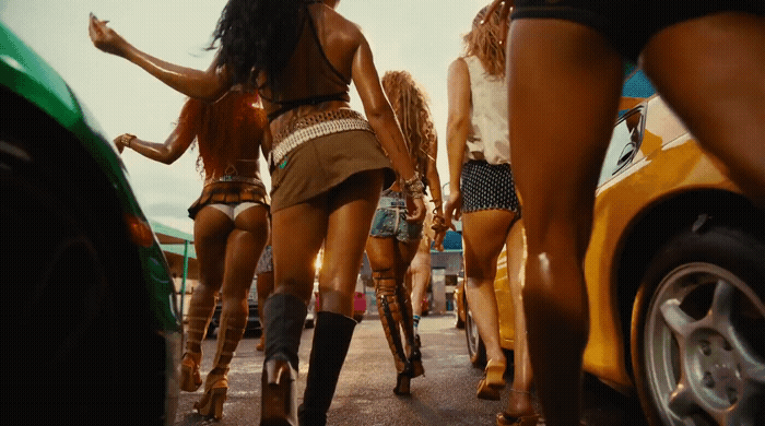 a group of women walking down a street next to a green car