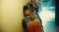 a woman with dreadlocks leaning against a wall