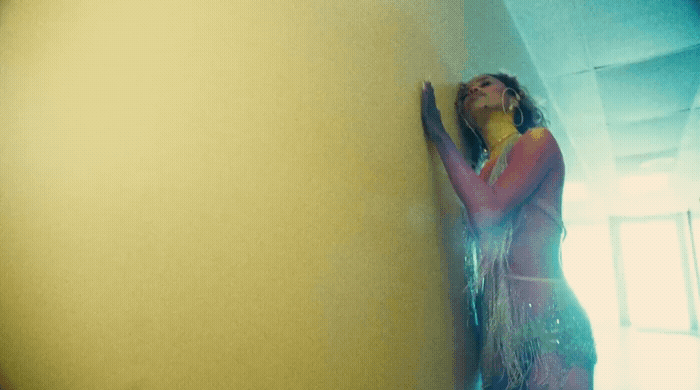 a woman in a long dress leaning against a wall