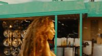 a woman with long hair walking past a store