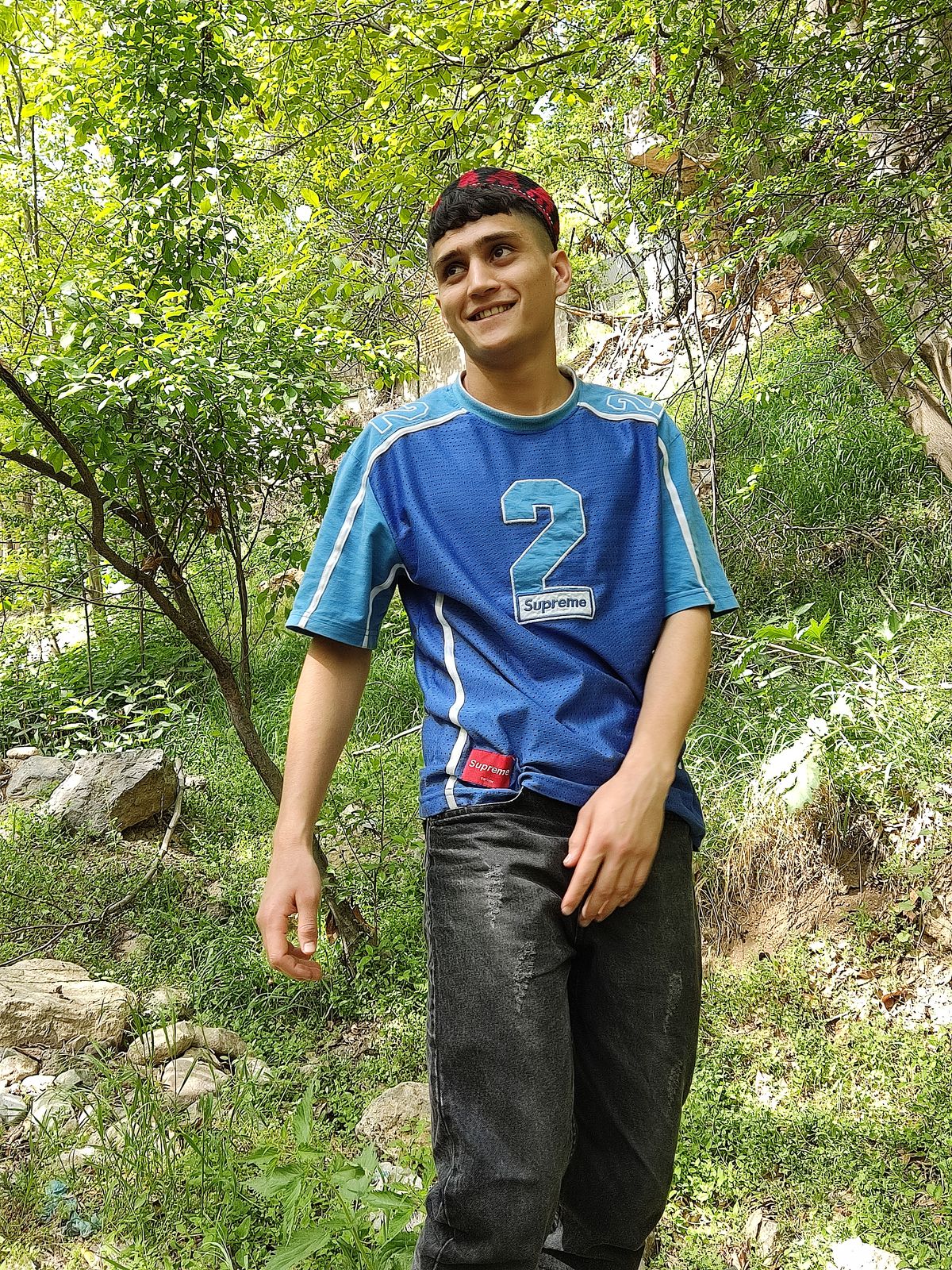 a man in a blue shirt standing in the woods