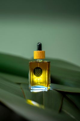a bottle of perfume sitting on top of a leaf