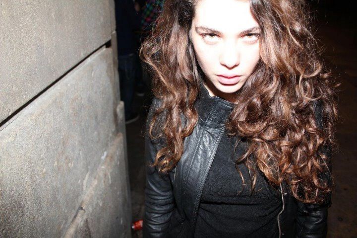 a woman with long curly hair and a leather jacket