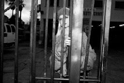 a woman behind bars in a jail cell