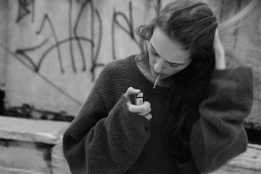 a woman smoking a cigarette and looking at her cell phone