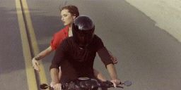 a man and a woman riding on the back of a motorcycle