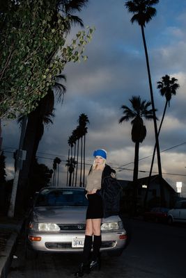 a woman standing on the side of a road next to a car