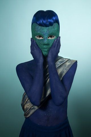 a woman with blue hair and a green mask covering her face