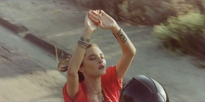 a woman in a red shirt holding her hands up in the air