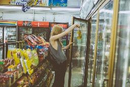 a woman reaching into a glass door in a store