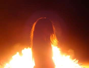 a woman standing in front of a large fire