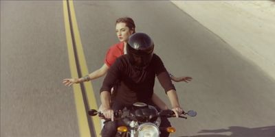 a man riding a motorcycle down a street next to a woman