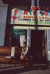 a man sitting on a chair in front of a flower shop