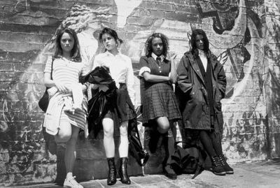 a group of women standing next to a brick wall