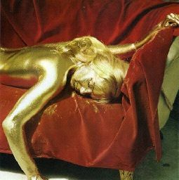 a woman covered in gold is laying on a couch