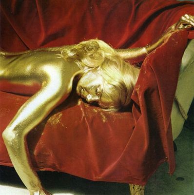 a woman covered in gold paint laying on a couch