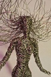 a wire sculpture of a woman with her hair blowing in the wind