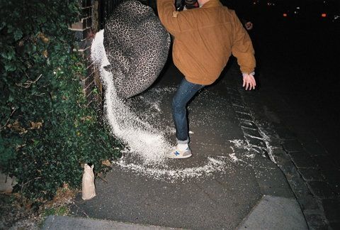 a man in a brown jacket is throwing snow into the air