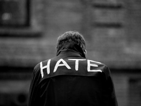 a man standing in front of a building with the word hate written on it