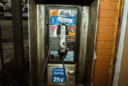 an old fashioned pay phone in front of a brick wall