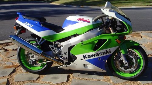 a green, white and blue motorcycle parked on the side of the road