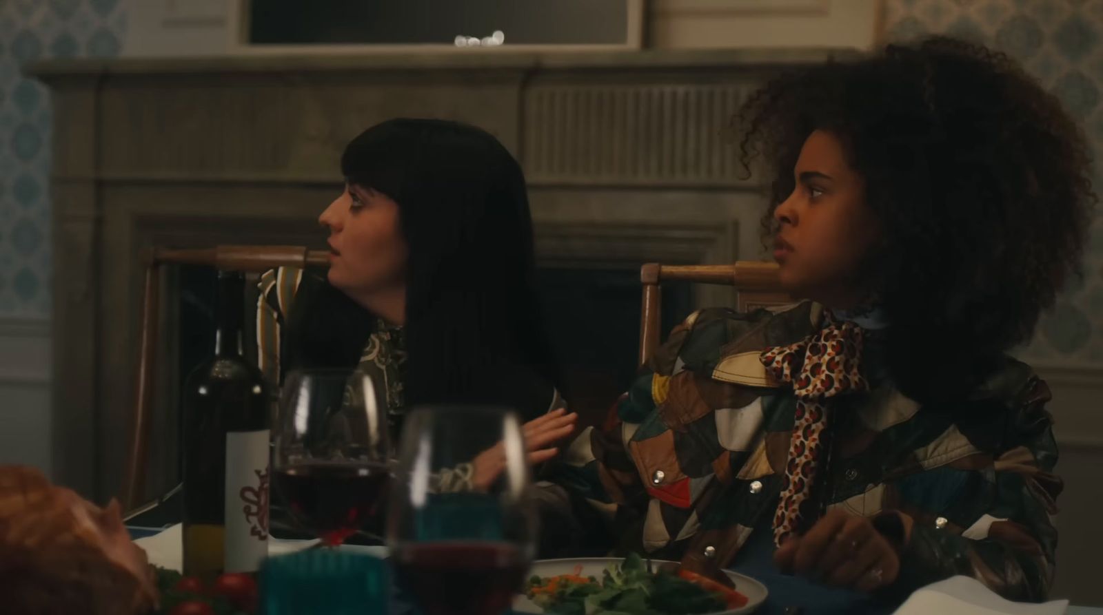 two women sitting at a table with food and drinks