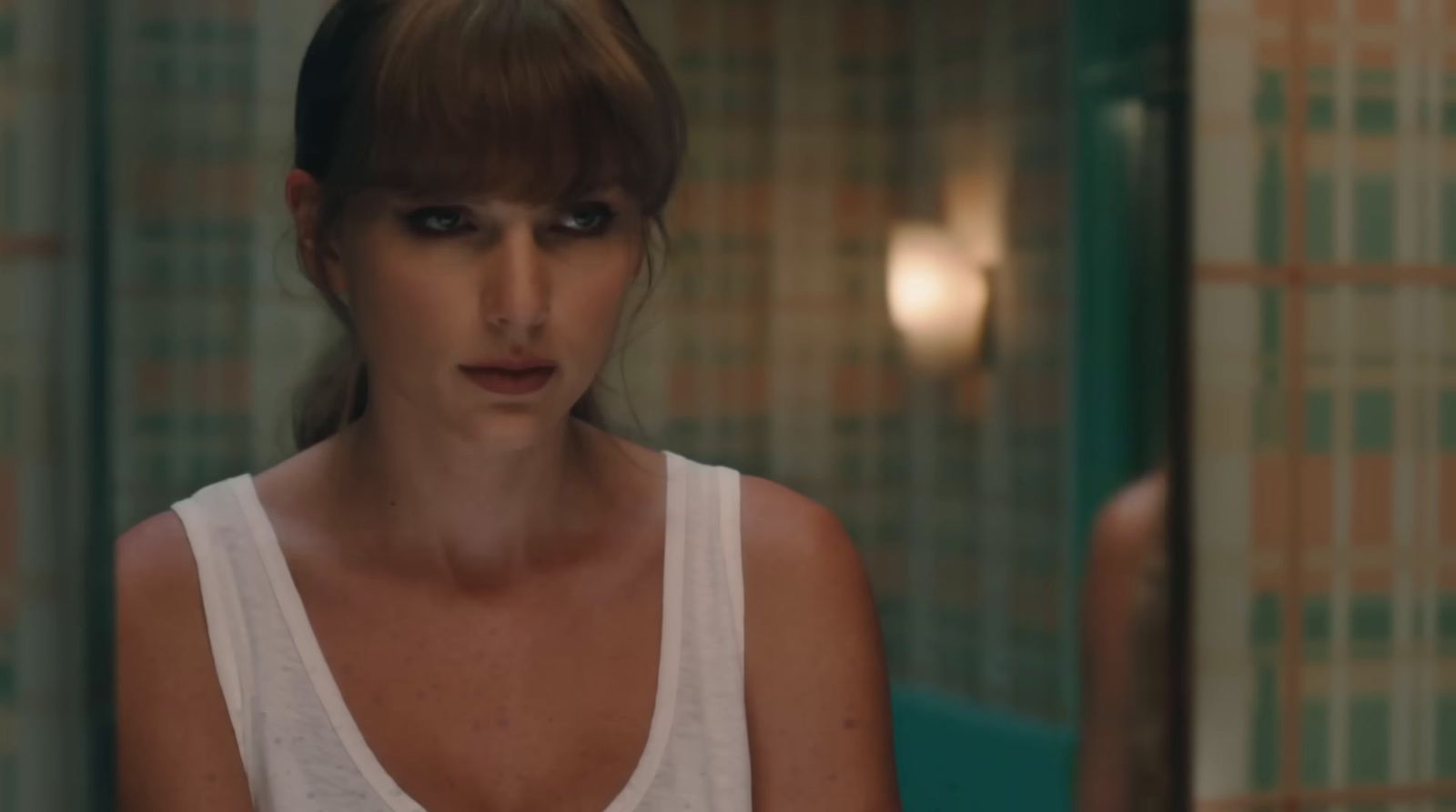 a woman in a white tank top in a bathroom