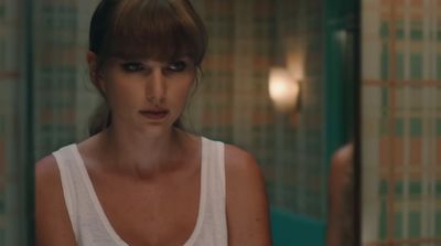 a woman in a white tank top in a bathroom