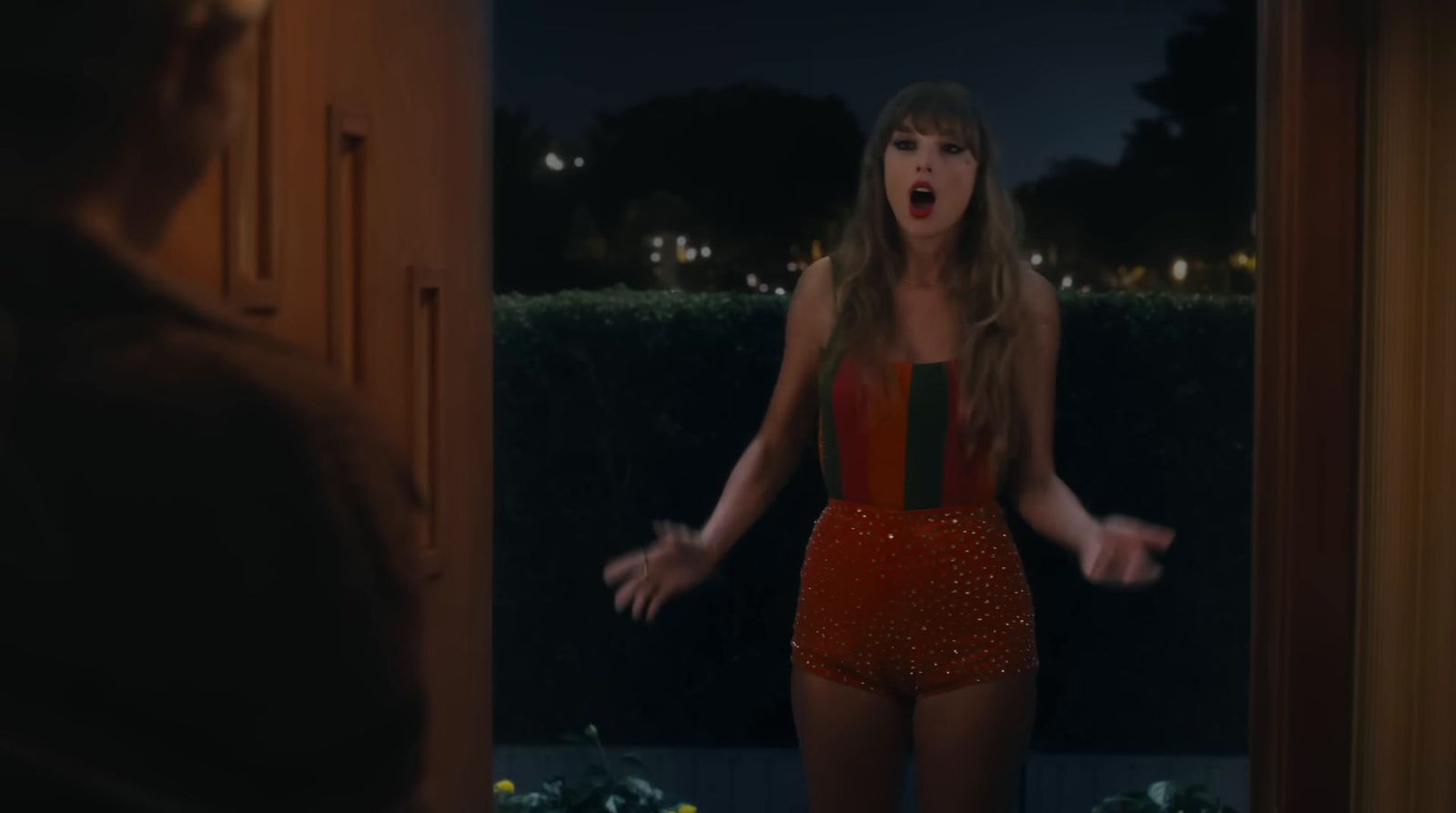 a woman in a red bodysuit standing in a doorway